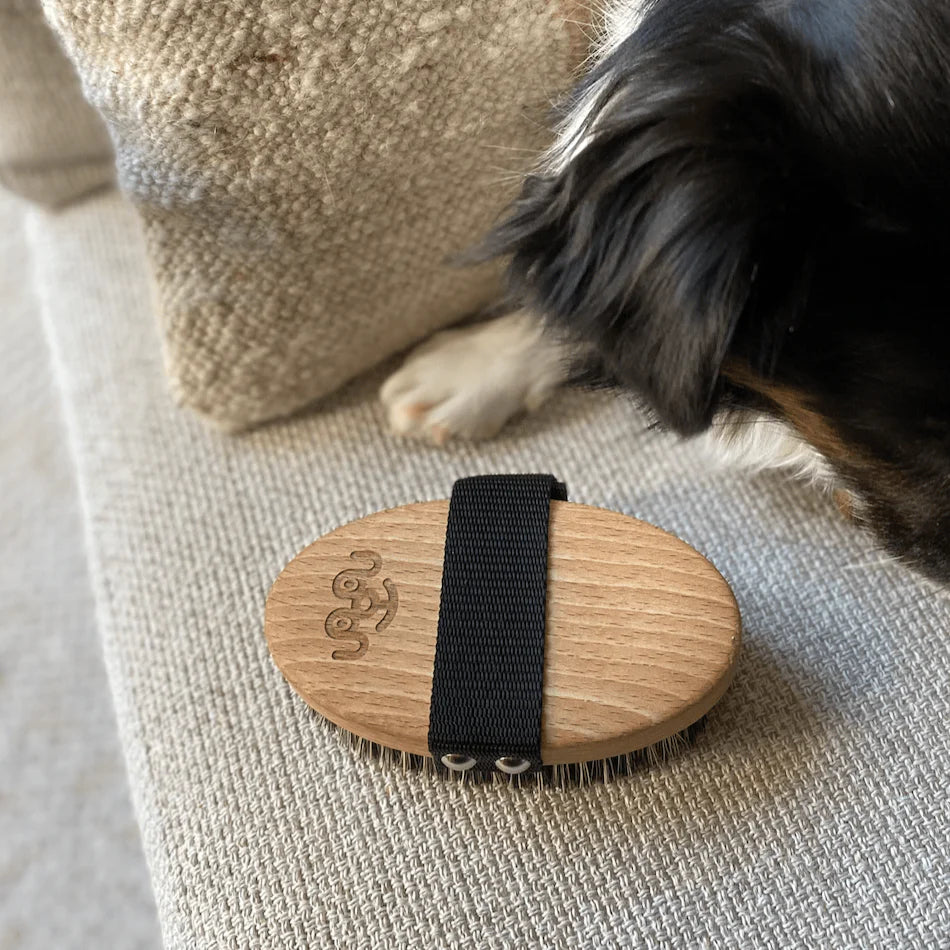 Detail of the smooth, eco-friendly wooden handle of the brush, showcasing the ergonomic design for a comfortable grip during extended gentle dog grooming.